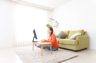 Evde bilgisayar kullanan genç bir kadın.