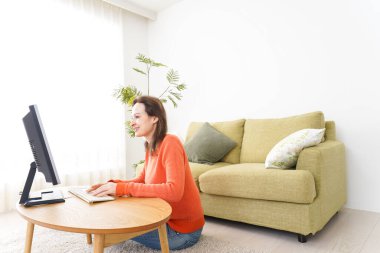 Evde bilgisayar kullanan genç bir kadın.