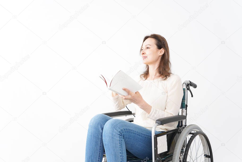 Young woman in a wheelchair reading books