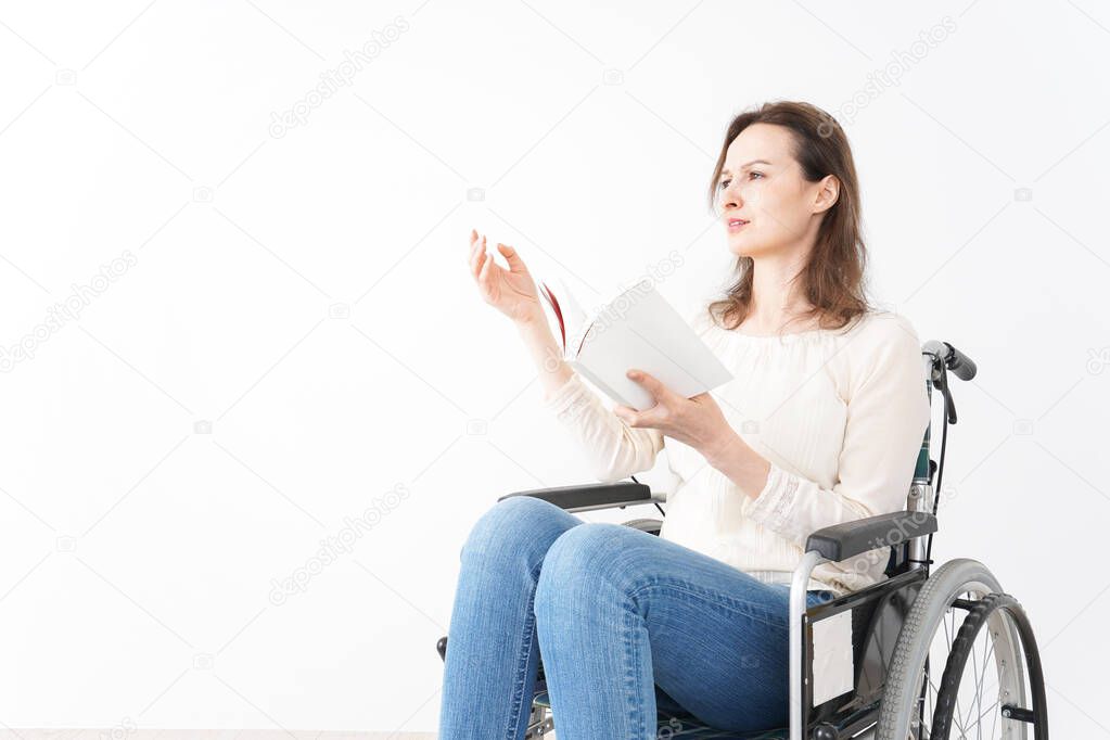 Young woman in a wheelchair reading books