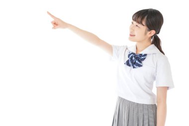 gülümseyen genç Asyalı kız öğrenci bir şeyi işaret ediyor 