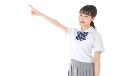 gülümseyen genç Asyalı kız öğrenci bir şeyi işaret ediyor 