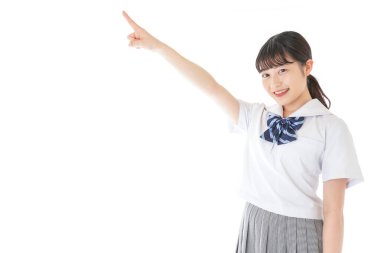 gülümseyen genç Asyalı kız öğrenci bir şeyi işaret ediyor 