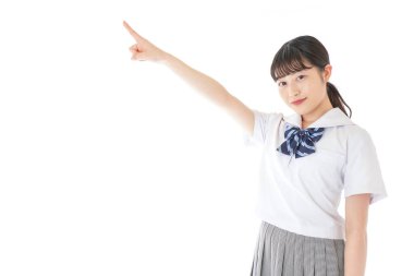 gülümseyen genç Asyalı kız öğrenci bir şeyi işaret ediyor 