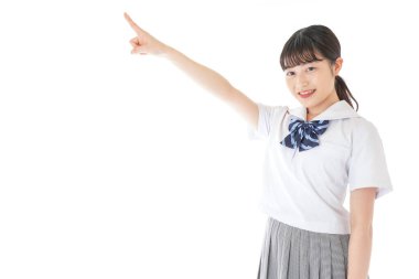 gülümseyen genç Asyalı kız öğrenci bir şeyi işaret ediyor 