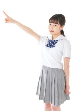 gülümseyen genç Asyalı kız öğrenci bir şeyi işaret ediyor 