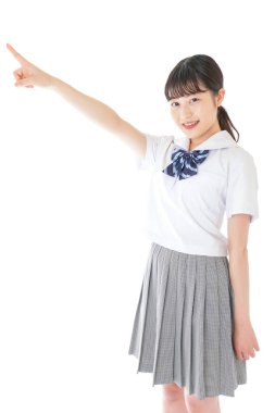 gülümseyen genç Asyalı kız öğrenci bir şeyi işaret ediyor 