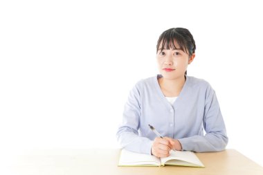 Genç Asyalı kız öğrenci masada oturuyor. 