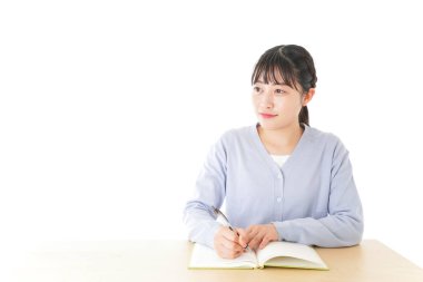 Genç Asyalı kız öğrenci masada oturuyor. 