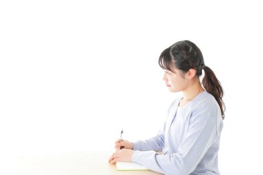 Genç Asyalı kız öğrenci masada oturuyor. 