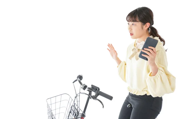 スマートフォンを使って自転車に乗る若い女性 — ストック写真