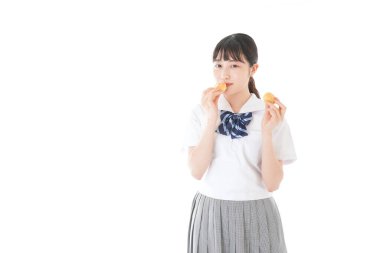 Üniformalı genç öğrenci abur cubur yiyor ve çalışıyor.