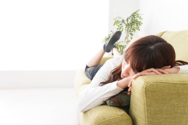 Evdeki kanepede dinlenen genç bir kadın.