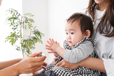 Anne ve bebeği hastanede muayene oluyor, doktor bebeği muayene ediyor. 