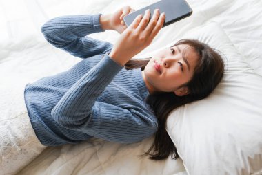 Yatmadan önce akıllı telefon kullanan genç bir kadın. 