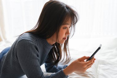 Yatmadan önce akıllı telefon kullanan genç bir kadın. 