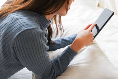 Yatmadan önce akıllı telefon kullanan genç bir kadın. 