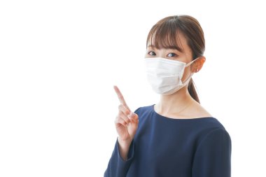 Bir şey gösteren maskeli genç bir kadın.