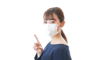 Bir şey gösteren maskeli genç bir kadın.