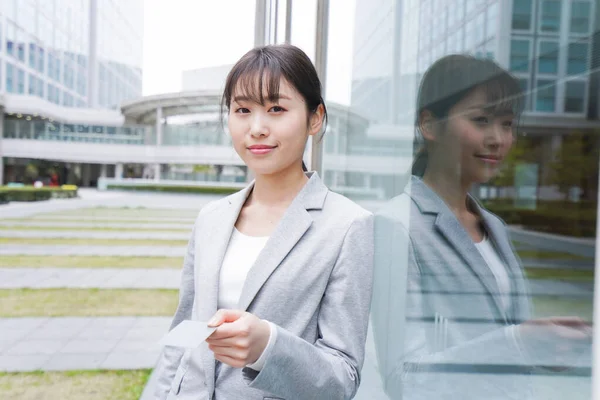 young businesswoman standing near office building with a credit card, a woman paying with cashless