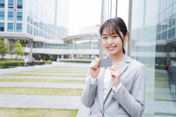 young businesswoman standing near office building with a credit card, a woman paying with cashless