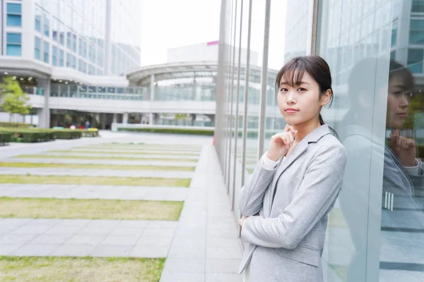 young businesswoman standing near office building and thinking about something