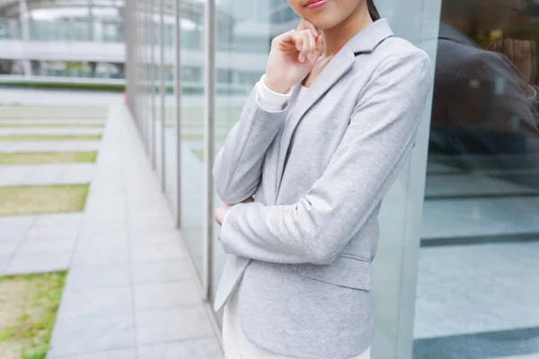 young businesswoman standing near office building and thinking about something