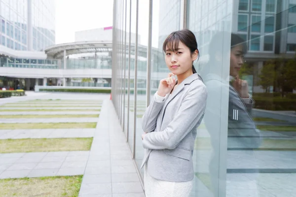 young businesswoman standing near office building and thinking about something