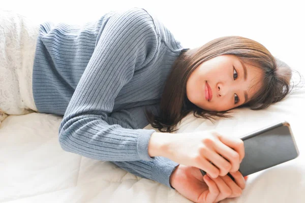 Young woman using smartphone in bed before going to sleep
