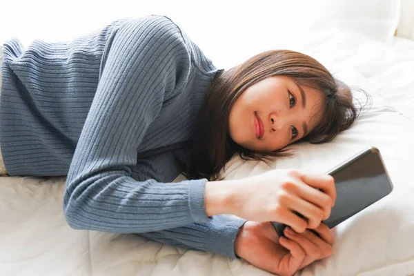 Young woman using smartphone in bed before going to sleep