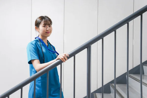 Young Asian nurse on stairs