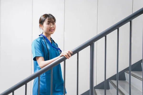 Young Asian nurse on stairs