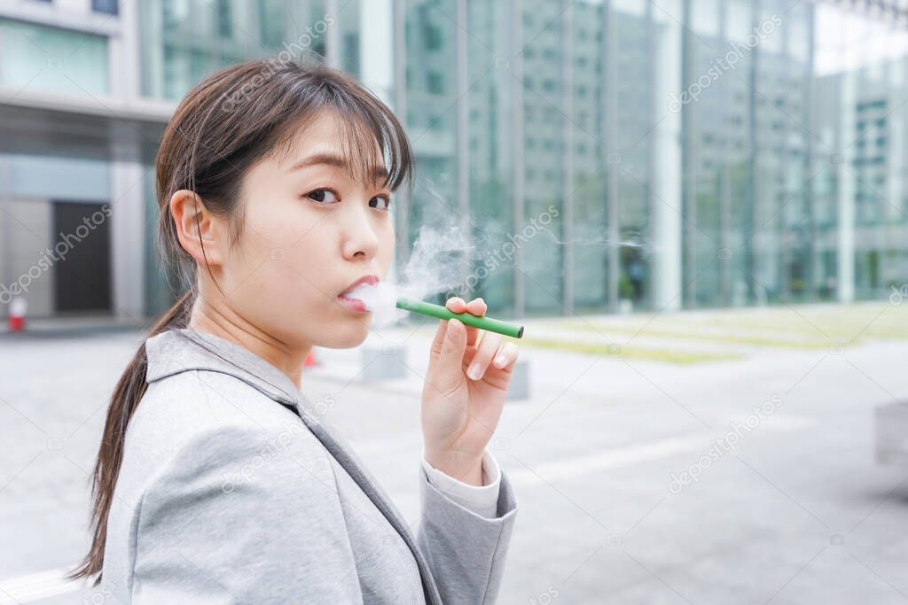 Young business woman smoking electronic cigarette