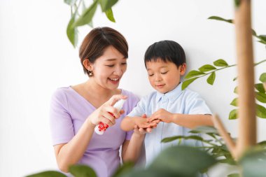  Anne çocuğunun ellerini sterilize etmek için sprey kullanıyor.