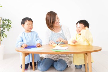 Çocuklar ve öğretmenler anaokulunda origami yapıyorlar.