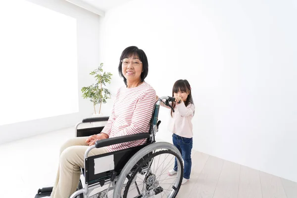 Asyalı küçük kız ve tekerlekli sandalyedeki yaşlı kadın.