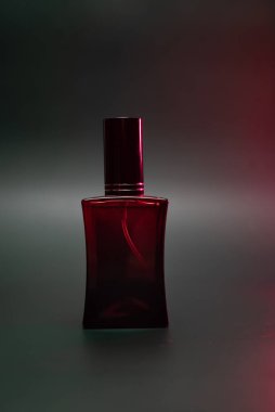 Siyah arka planda kırmızı bir şişede buharlı parfüm.