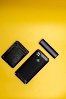 Akıllı telefon deri cüzdanı ve sarı arka planda elektronik sigara.