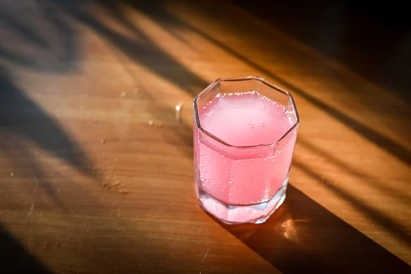 Copo de vidro com coquetel rosa na mesa de madeira — Fotografia de Stock