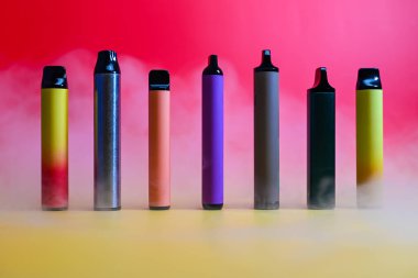 çok renkli elektronik sigaralar dumandaki kırmızı arka planda.