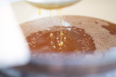 Altın nektarla doldurulmuş altıgen bal peteklerinden bir damla bal damlıyor. Bal peteği yaz kompozisyonu. Doğal bal damlası, balmumu çerçeveli arı damlası. Bal damlası bal damlatıyor bal peteğine.