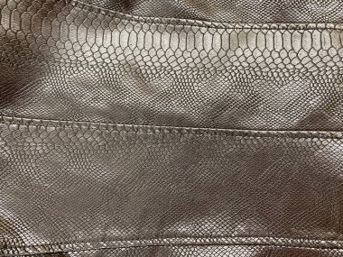 Açık bej, gümüş, açık kahverengi deri kumaş, bazı kıyafetler, deri ceket, büyük dikişler. Yapay deri yılan derisi gibi görünüyor, timsah derisi.