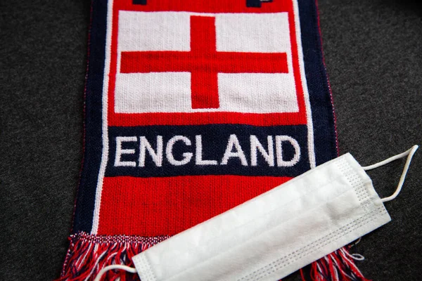 White mask, next to the scarf of a Great Britain football fan with the inscription England on it