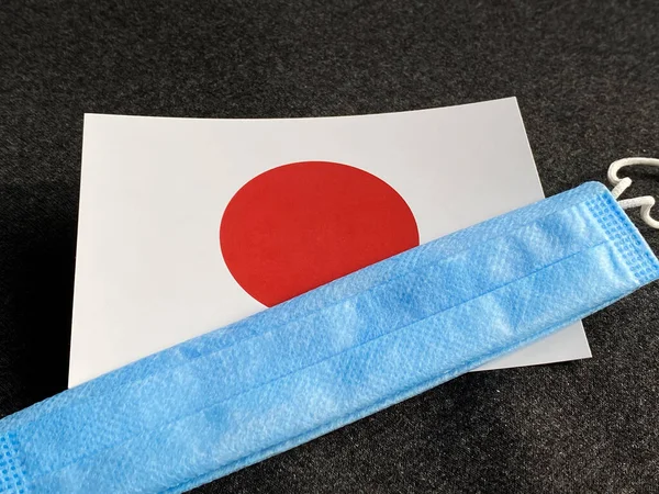 Japan, Japanese flag is near a blue mask on the dark gray background. Tourist trip. European Football Championship, Euro