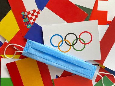 Mari El, Rusya - 12 Haziran 2021: Olimpiyat bayrağı dünya bayraklarında tıbbi mavi maskenin yanında. Tokyo 2020 yarışmaları. Turist gezisi. Şampiyonluk