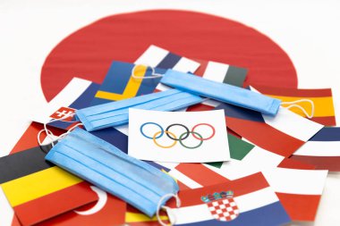 Mari El, Rusya - 16 Haziran 2021: Olimpiyat bayrağı ve halkaları, Japon bayrak arka planında mavi bir maske var. Turist gezisi. Şampiyonluk, Olimpiyatlar
