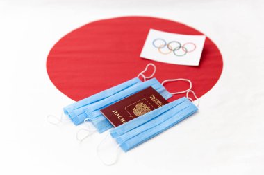 Mari El, Rusya - 16 Haziran 2021: Kırmızı turda Olimpiyat bayrağı. Rus pasaportu ve mavi maskeler. Japon bayrağı arka planı. Turist gezisi. Olimpiyat Oyunları