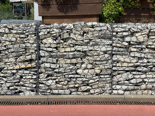 Gabion. Fence made of stone in a metal mesh. Welded galvanized gabion. House and path