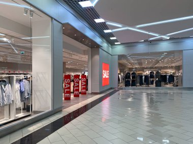 Satış döneminde büyük bir giyim mağazasına giriş. Büyük yazıtlar, satış. Elektronik madde gözetiminde satılan kelimeler. Kimse yok.