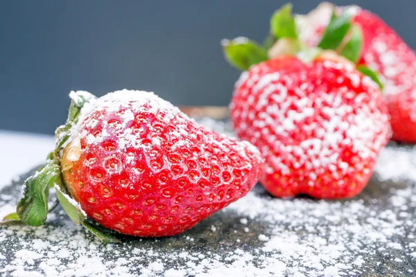 Fresas rojas grandes en azúcar en polvo blanco sobre un fondo gris piedra, imagen de color de contraste con espacio para el texto. bayas sofisticadas . — Foto de Stock